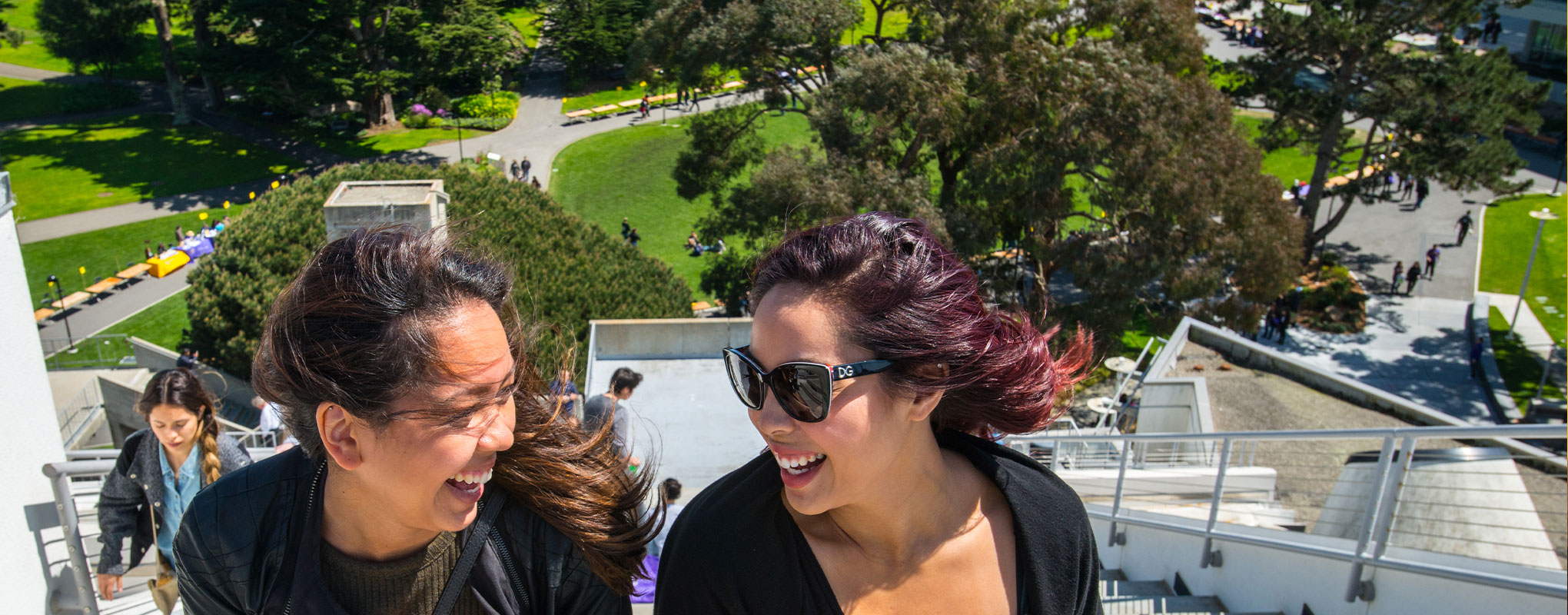 Two students laughing together on a bright windy day