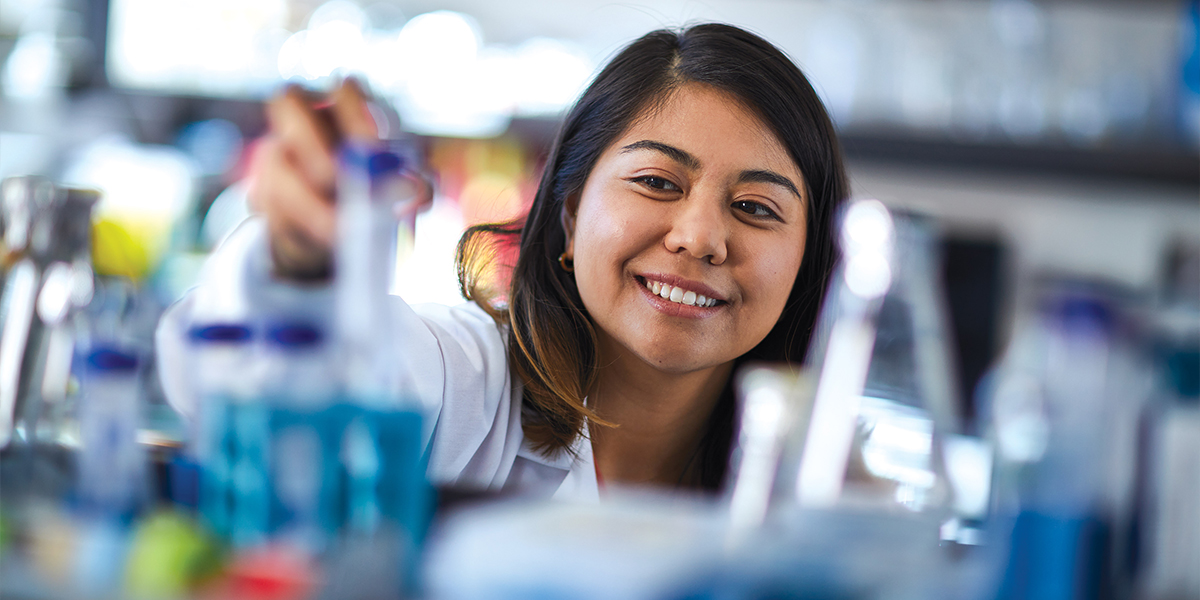 Science student reaching for vial