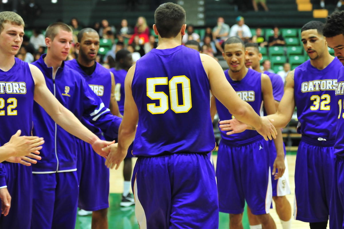 Men's basketball players in a group clapping one another's hands