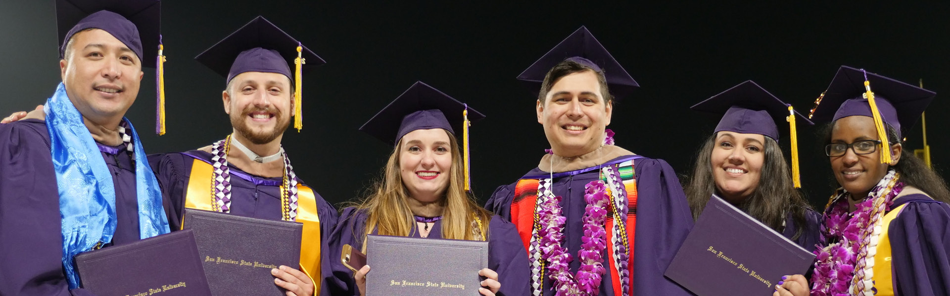 Six alumni wearing their purple regalia